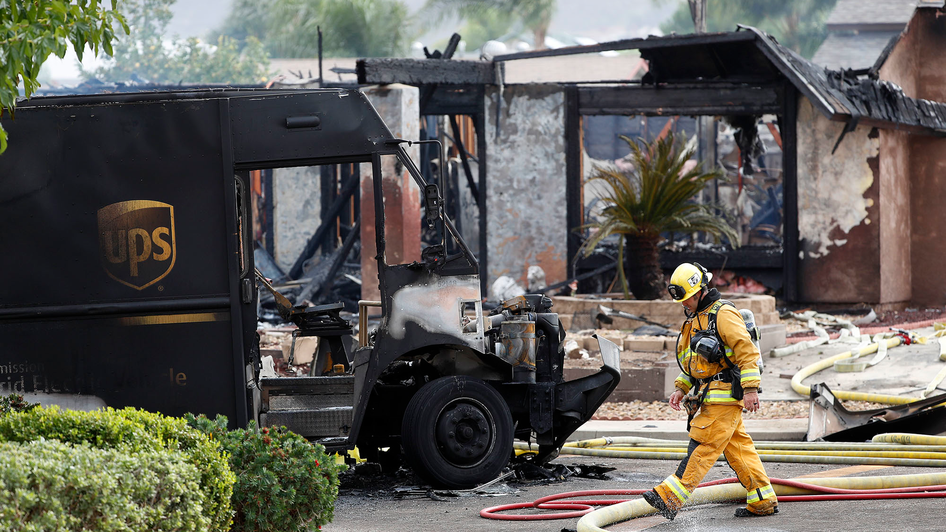 A burned-out UPS delivery truck sits in front of a smoldering home after a plane crash in Santee, CA, that killed two people, including the UPS driver, on Monday, Oct. 11, 2021.