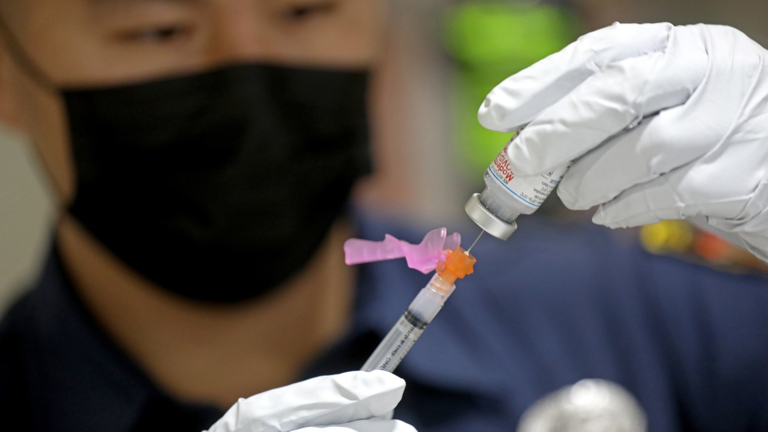 An LAFD paramedic prepares a dose of the Moderna COVID-19 vaccine for a firefighter in December 2020.