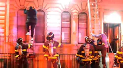 FDNY firefighters assist victims down fire escapes and ground ladders during a two-alarm fire in Harlem.