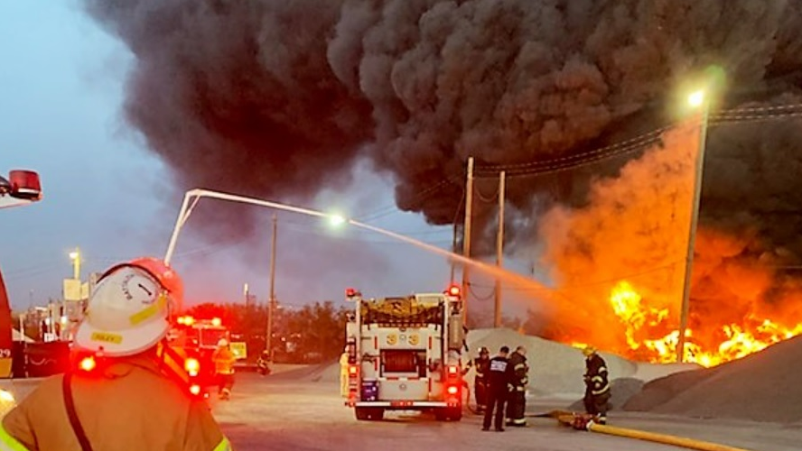Firefighters use elevated waterways to control a multiple-alarm fire at a recycling center.