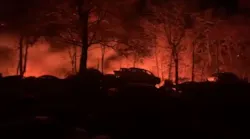 Flames glow in the background during a five-alarm fire in Smithfield, RI, on Monday, Nov. 15, 2021.
