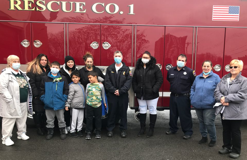 Family gathers with two of the Syracuse firefighters who saved three of them when from a 1998 apartment fire. From left: Lori Holmes, Christina Micheletti, Brendan Roberts, Allayna Johnson, Anna Curtis, Mason and Quentin Johnson, Mark Hatch, Jordan Micheletti, Bob Tangredi, Lisa Curtis, and Lisa Micheletti.