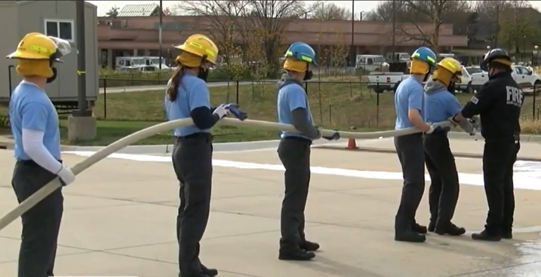 High school students train with Overland Park firefighters earning fire service certifications.