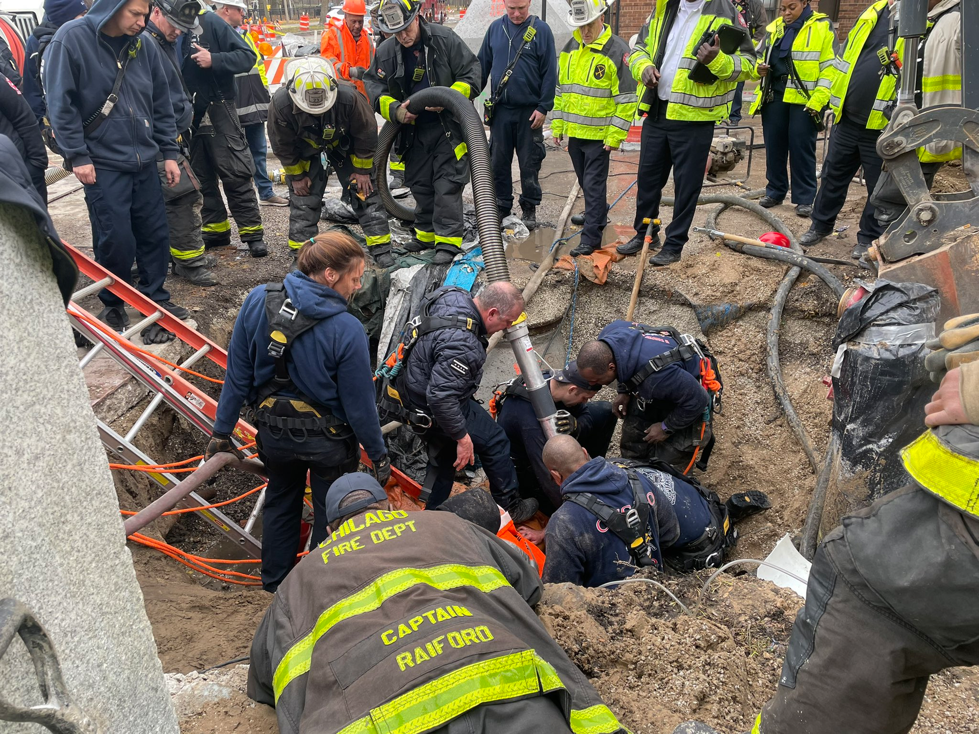 Firefighters use a vacuum connection to remove debris to free the worker.