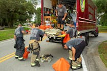 Pasco County, FL, Fire Rescue (PCFR) members swap turnout gear that they wore for a structure fire for a clean set of gear that a decon technician brought to the scene.