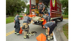Pasco County, FL, Fire Rescue (PCFR) members swap turnout gear that they wore for a structure fire for a clean set of gear that a decon technician brought to the scene.