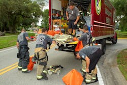 Pasco County, FL, Fire Rescue (PCFR) members swap turnout gear that they wore for a structure fire for a clean set of gear that a decon technician brought to the scene. Pasco County, FL, Fire Rescue (PCFR) members swap turnout gear that they wore for a structure fire for a clean set of gear that a decon technician brought to the scene.