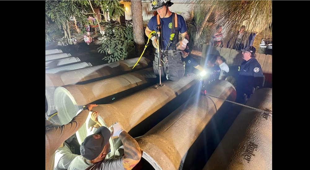 Fire crews prepare to use a chisel to free a trapped child from a concrete pipe.