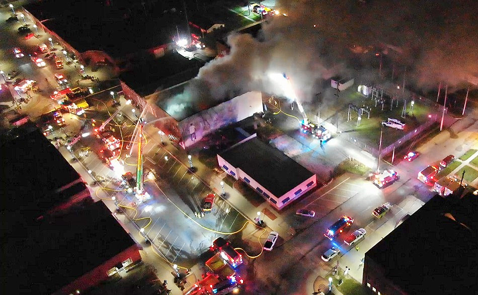 Firefighters use multiple aerial devices to control fire in a downtown building.