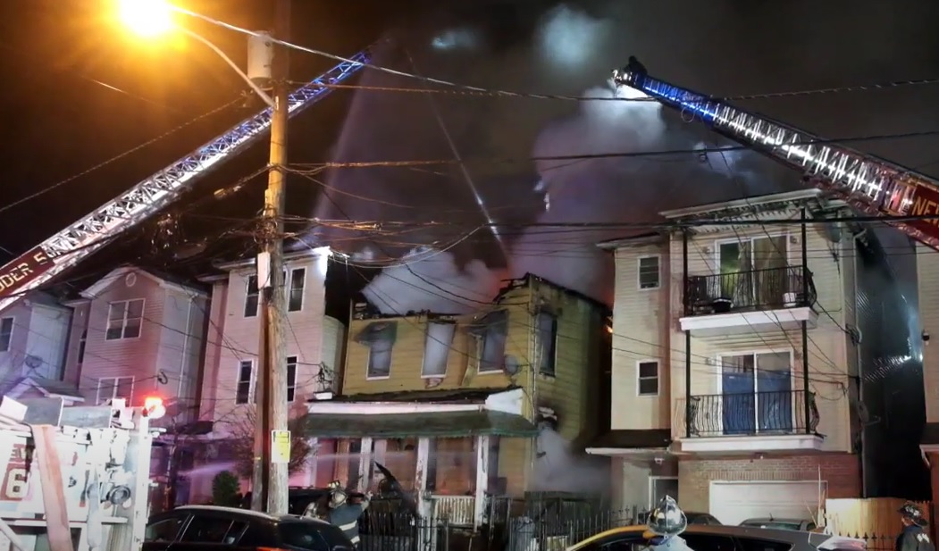Firefighters use aerial devices to extinguish fire that damaged three Newark homes.