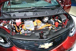 A responder who opens the hood of a Chevrolet Bolt will see orange cables and connectors. They indicate the presence of high voltage. Note the additional sticker to the left of the hood latch. It is applied by the automaker and identifies the location of the two batteries on the EV.