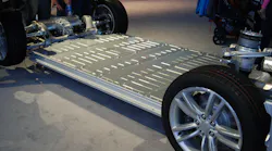 Shown is the floorpan-mounted, high-voltage lithium-ion battery pack of a Tesla Model S sedan. The completed body of the vehicle is placed onto this battery pack. The electric motor, shown at upper left, drives both rear-axle wheels.
