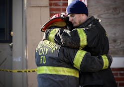 Firefighters hug at the scene of the South Stricker rowhome fire Monday morning.