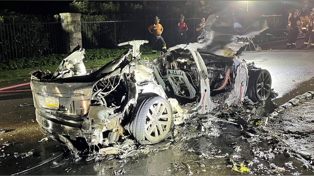 After initial knockdown, the remains of a burnt Tesla Model S received copious amounts of water for almost two hours. Note some of the more than 7,000 rechargeable battery cells on the street in the runoff from this fire.