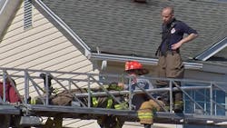 Firefighters work to free Richard Schuller after his feet got caught in an aerial ladder during a duplex fire Monday.