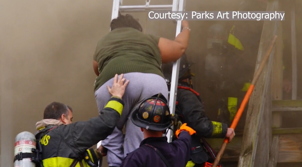 Saint Louis firefighters assist an home fire occupant down a ladder to safety.