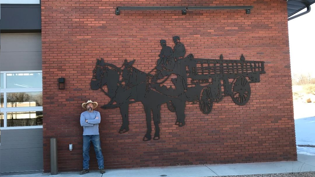 Artist Jeff Bates stands adjacent to his artwork now displayed at Grand Junction Fire Station 6.