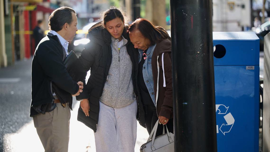 Leticia Harris, center, whose husband Sergio Harris was killed in the mass shooting in downtown Sacramento early Sunday, speaks with a police detective, left, while his mother Pamela Harris sobs.