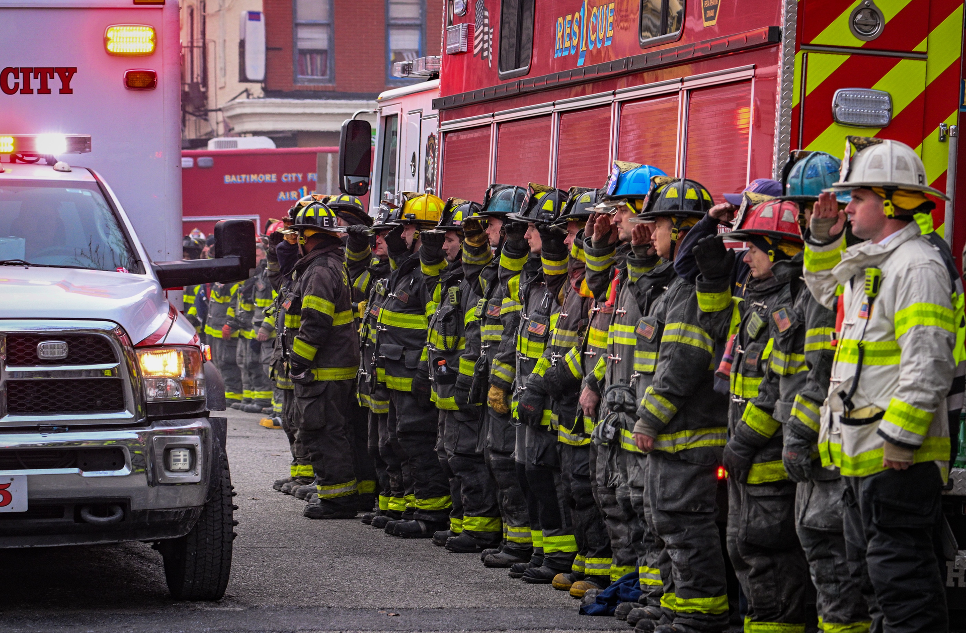 Baltimore City firefighters salute as an ambulance carries the body of Lt. Paul Butrim from the scene of a vacant row house fire on S. Stricker Street. Four firefighters were trapped in a collapse while fighting the fire Monday morning. Three have died and a fourth is in critical condition.