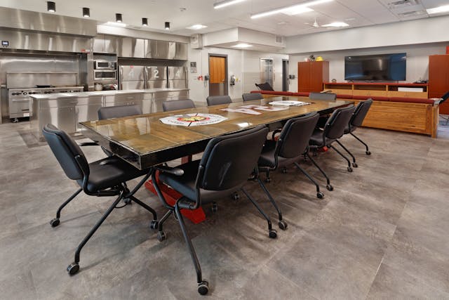 This department&rsquo;s standards called for resilient flooring, a stainless steel kitchen and lounge furniture in the dayroom. By adding decorative task lighting above the island, defining space with soffits, procuring a custom dining table, installing stone-look resilient flooring, specifying residential-style ceiling fans and using red accents in upholstery, the spaces feel more inviting but very much still a fire station.