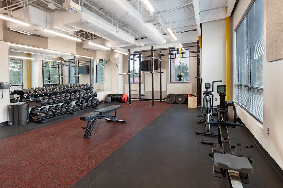 Acoustic wall panels, high-performance paint and recycled-rubber athletic flooring were design standards for this department. Selecting a flooring that met performance requirements but had a pop of color and combining that with an exposed ceiling, a punch of safety yellow on interior steel columns and access to daylight with sun control yielded a lively physical conditioning room.