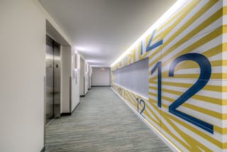 Fire stations and training facilities have high-use corridors. Durable wall protection is critical. Here, printed metal panels, stainless steel wall corner guards and resilient wall base contribute to that protection while upping the aesthetic. Wall-washing recessed lights and repetitive sconces, instead of generic troffers, do, too.