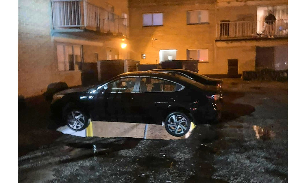 A vehicle is suspended by its bumpers after the decking collapsed into the garage below.
