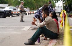 A sheriff checks his phone as he sits on the sidewalk outside Robb Elementary School in Uvalde. A sheriff checks his phone as he sits on the sidewalk outside Robb Elementary School in Uvalde.