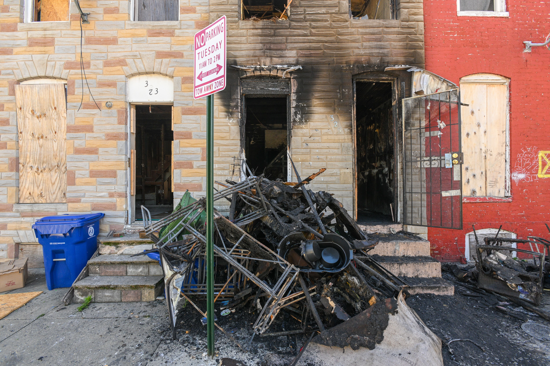 Charred furniture is piled in front of a vacant rowhouse on Furrow Street in the Carrollton Ridge neighborhood in West Baltimore a day after firefighters responding to a fire found a man dead with gunshot wounds in the building.