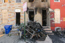 Charred furniture is piled in front of a vacant rowhouse on Furrow Street in the Carrollton Ridge neighborhood in West Baltimore a day after firefighters responding to a fire found a man dead with gunshot wounds in the building.