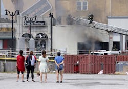 Beachgoers watch as firefighters battle a fire on the Boardwalk in Atlantic City on Friday morning. Beachgoers watch as firefighters battle a fire on the Boardwalk in Atlantic City on Friday morning.