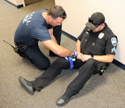 A firefighter/paramedic practices placing a training tourniquet on a law enforcement officer. Firefighters should become familiar with the locations that law enforcement officers carry their tourniquets. A firefighter/paramedic practices placing a training tourniquet on a law enforcement officer. Firefighters should become familiar with the locations that law enforcement officers carry their tourniquets.