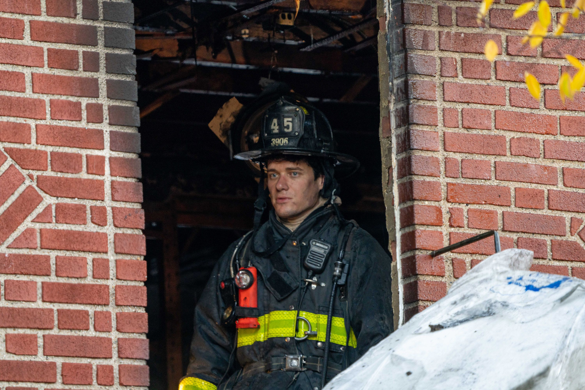 An FDNY firefighter peers out a window of a house where three died Sunday.