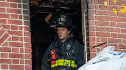 An FDNY firefighter peers out a window of a house where three died Sunday.