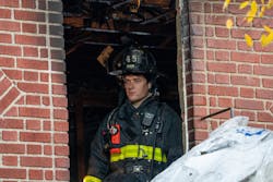 An FDNY firefighter peers out a window of a house where three died Sunday. An FDNY firefighter peers out a window of a house where three died Sunday.