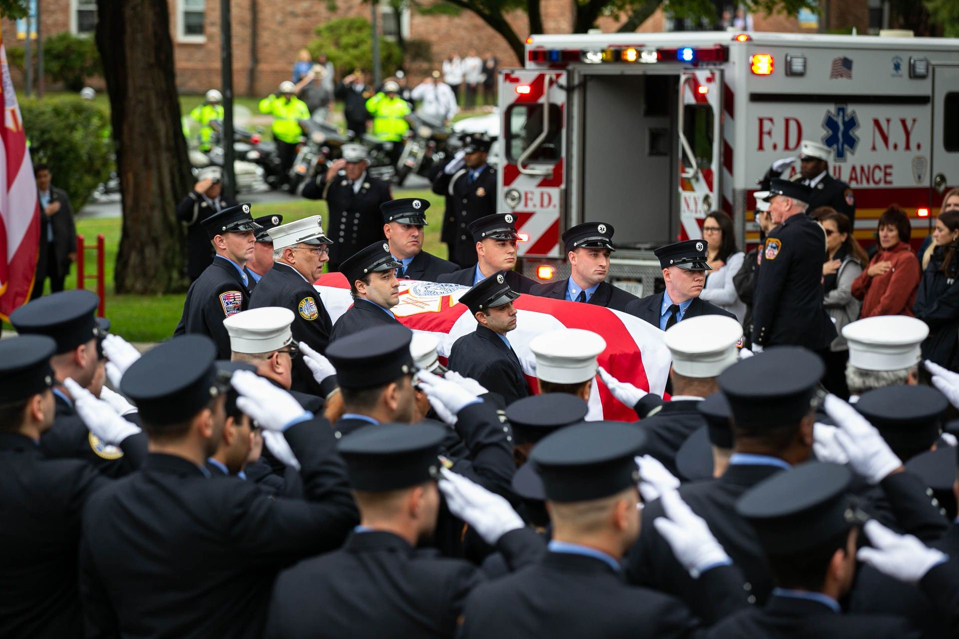 FDNY personnel salute as Capt. Alison Russo's casket is removed from the ambulance.