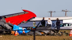 Dallas Fire-Rescue officials gather near the wreckage of a Boeing B-17 Flying Fortress and a Bell P-63 Kingcobra that crashed Saturday at the Dallas Executive Airport.