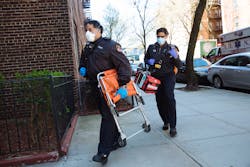 FDNY medics carry gear into a residence. FDNY medics carry gear into a residence.