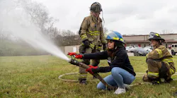 Joselin Barrera, student of Bryan Station High School, sprays a fire hose during the Brenda Cowan Camp with the assistance of firefighters Sarah McGill, center, and Megan Morrell, right.