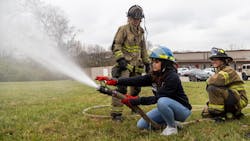 Joselin Barrera, student of Bryan Station High School, sprays a fire hose during the Brenda Cowan Camp with the assistance of firefighters Sarah McGill, center, and Megan Morrell, right. Joselin Barrera, student of Bryan Station High School, sprays a fire hose during the Brenda Cowan Camp with the assistance of firefighters Sarah McGill, center, and Megan Morrell, right.