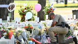 A police officer places flowers at a memorial outside Robb Elementary School in Uvalde, TX, on May 26, 2022.