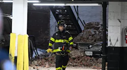 An FDNY firefighter walks past a car covered in rubble at the scene of a parking lot collapse in Manhattan Tuesday evening.
