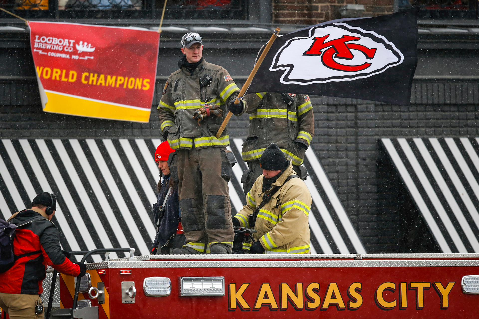 A firefighter waves a flag atop an engine during the 2020 Super Bowl parade.