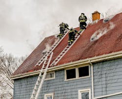 Two roof ladders that are placed approximately four feet apart provide the platform upon which two firefighters can make a Milwaukee cut to ventilate a house that has a steep roof.