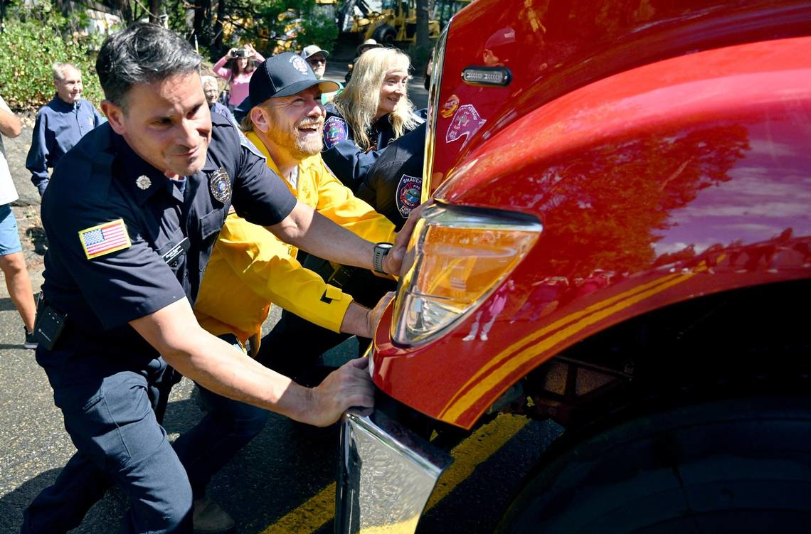 Shaver Lake firefighter David Eggers, left, with help from Fresno County Supervisor Nathan Magsig, push E-260 into the station.