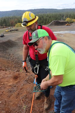 Brian Adams (right) of the Grangeville Mountain Rescue Unit shows Indian Valley Volunteer Fire Department engineer Josh Barritt how to tie into a rope prior to rappelling down the rock face.