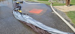 Students constructed a diversion using tarps, sandbags and charged fire hose to channel runoff away from a storm drain that they already protected using a chemical-resistant storm drain cover. Students constructed a diversion using tarps, sandbags and charged fire hose to channel runoff away from a storm drain that they already protected using a chemical-resistant storm drain cover.