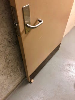 When deploying a door chock, it should be placed under the door on the latch side.