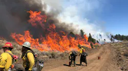 Firefighters engage in firing operations to reinforce a two-track road that’s being used for perimeter control.