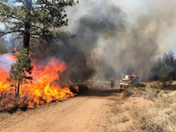 A Type 3 engine monitors a dirt road. It&rsquo;s utilizing limited water to reduce fire intensity, saving its tactical reserve for potential spot fires.